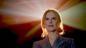 Nicole Kidman against an empty background, with only a movie projector illuminating her from behind, from AMC's ad about going back to the movies.