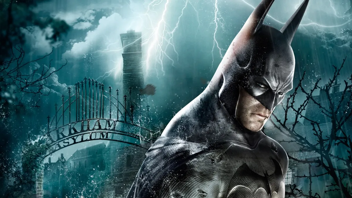 Batman stands in the rain in front of the gates of Arkham Asylum