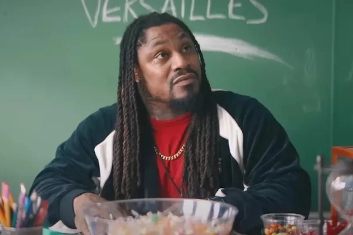 Marshawn Lynch sits at a teacher's desk in a scene from Bottoms.