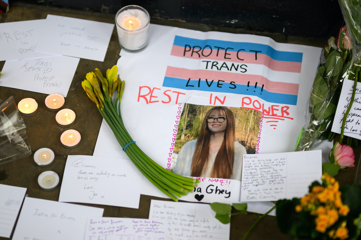 A memorial vigil with candles, flowers, and a photo of Brianna Ghey.