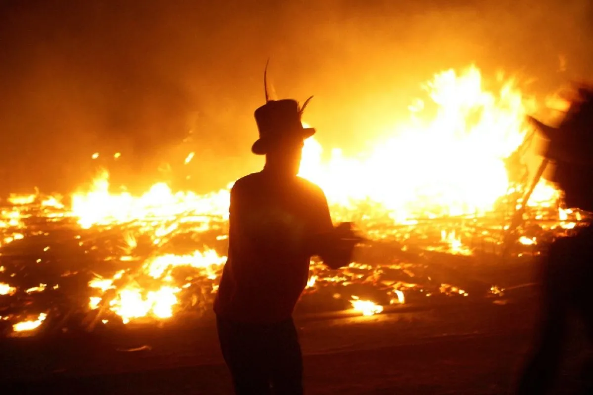 A figure silhouetted against flames in the background at Burning Man festival 2003.