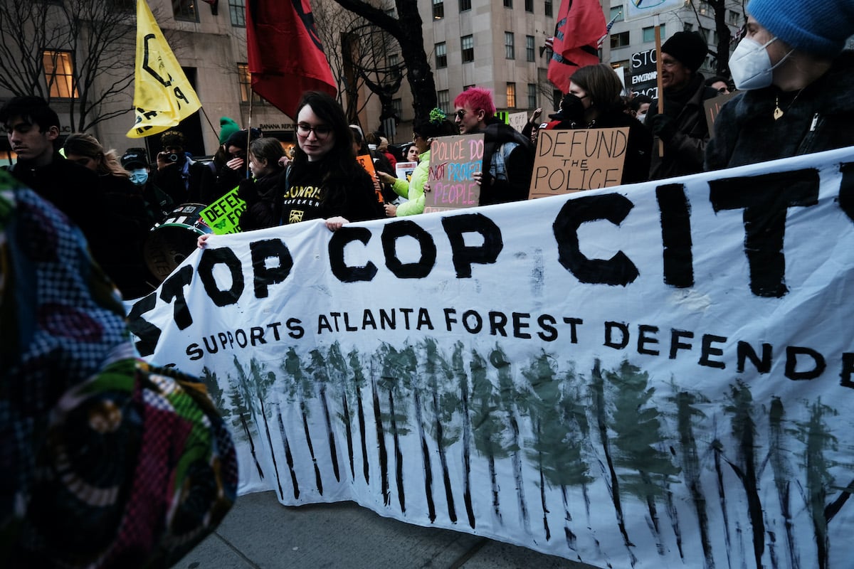 Protesters hold a large banner reading "Stop Cop City"