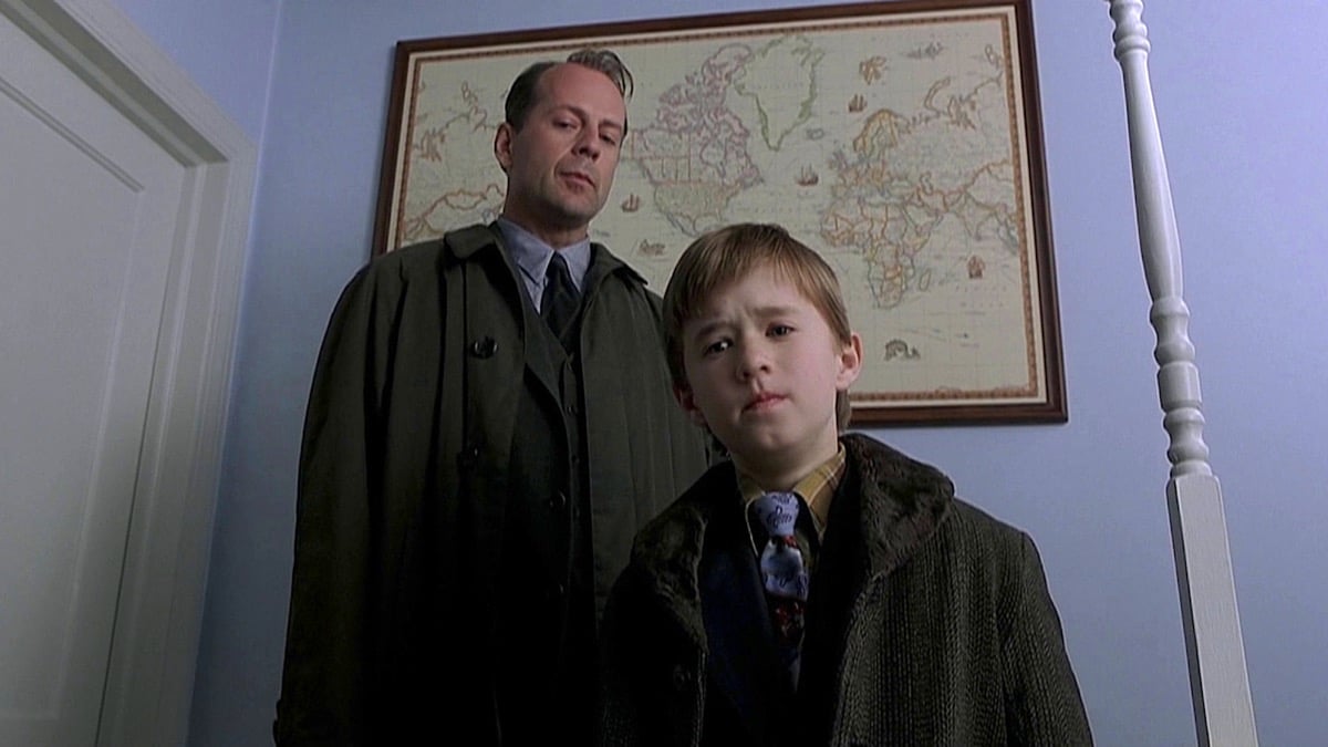 Haley Joel Osmet and Bruce Willis looking down at something curiously in "The Sixth Sense"