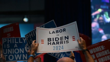 Supporters at a rally hold signs reading 
