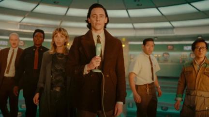 Loki stands with a microphone, with Mobius, B-15, Sylvie, Casey, and O.B. behind him.
