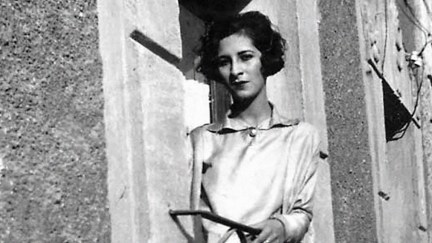 Luisa Moreno, wearing a white shirt and a short bobbed haircut, leans out of a balcony in a black and white photo.