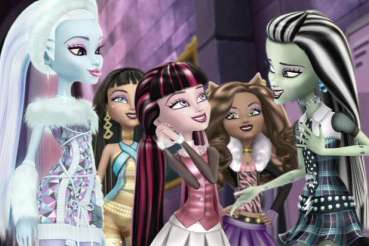 Monster High: Why Do Ghouls Fall in Love?; Abby Bominable, a blue skinned girl, stands behind Draculaura, a vampire with black and pink hair, both facing Frankie. Several other students stand behind them.