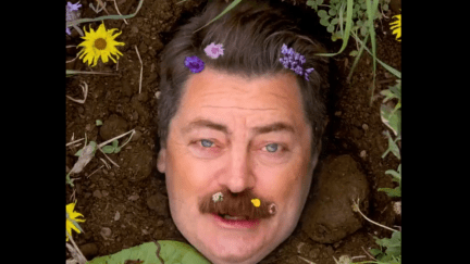 Nick Offerman's face pokes up from the soil, with flowers in his mustache and hair.