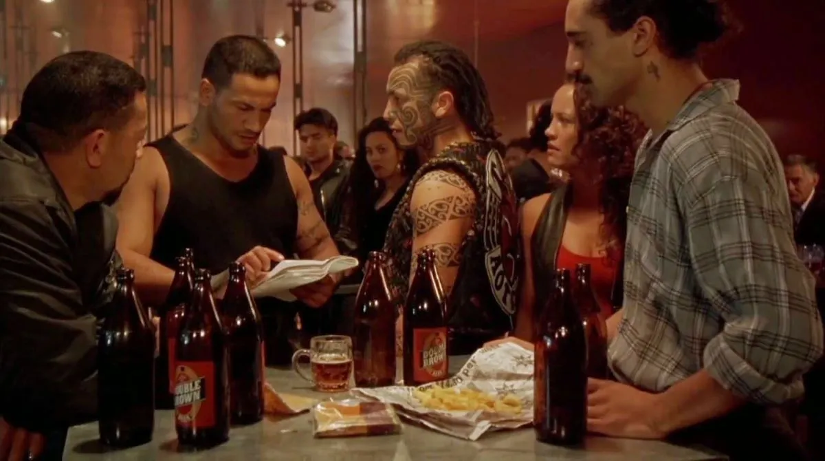 Jake, Beth, and others standing around a bar table in 'Once Were Warriors'.