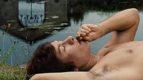 Oliver Quick (Barry Keoghan) smoking a cigarette by the lake in 'Saltburn'.