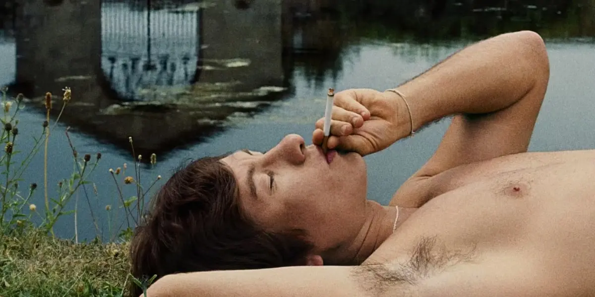 Oliver Quick (Barry Keoghan) smoking a cigarette by the lake in 'Saltburn'.