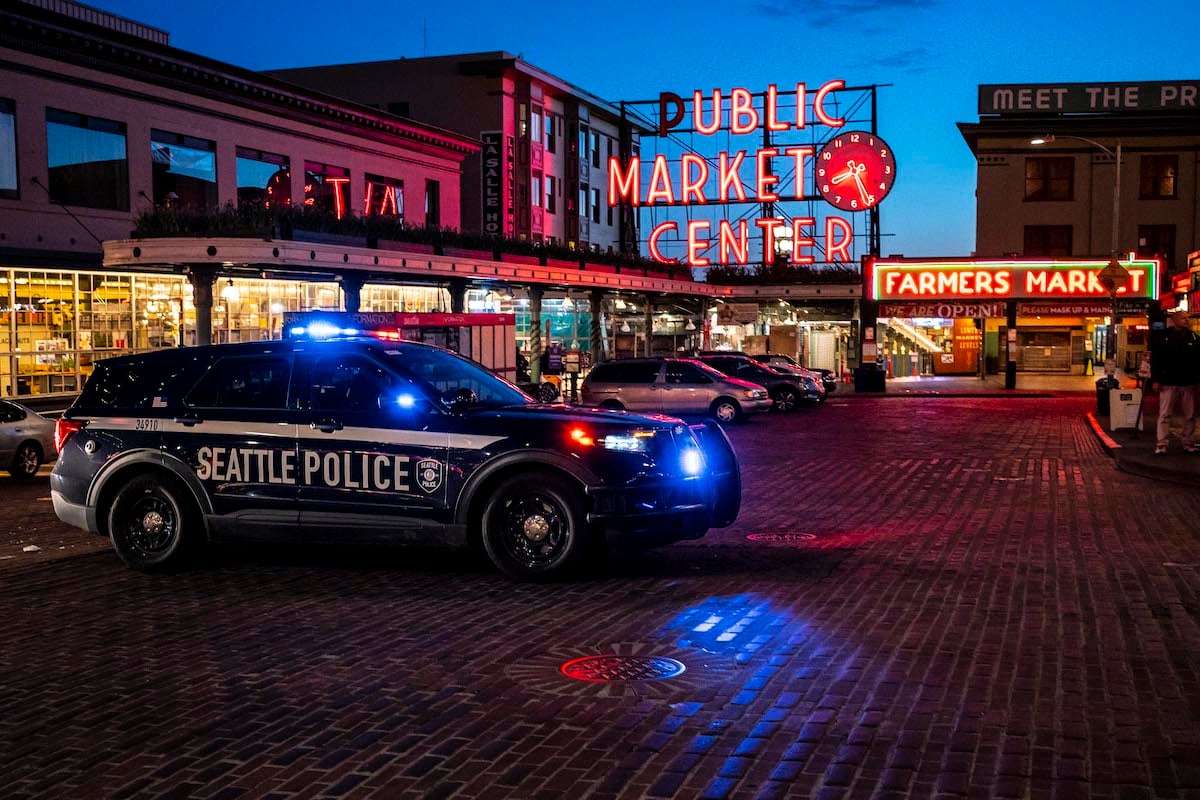 A police car sits in front of Seattle's Public Market at night.