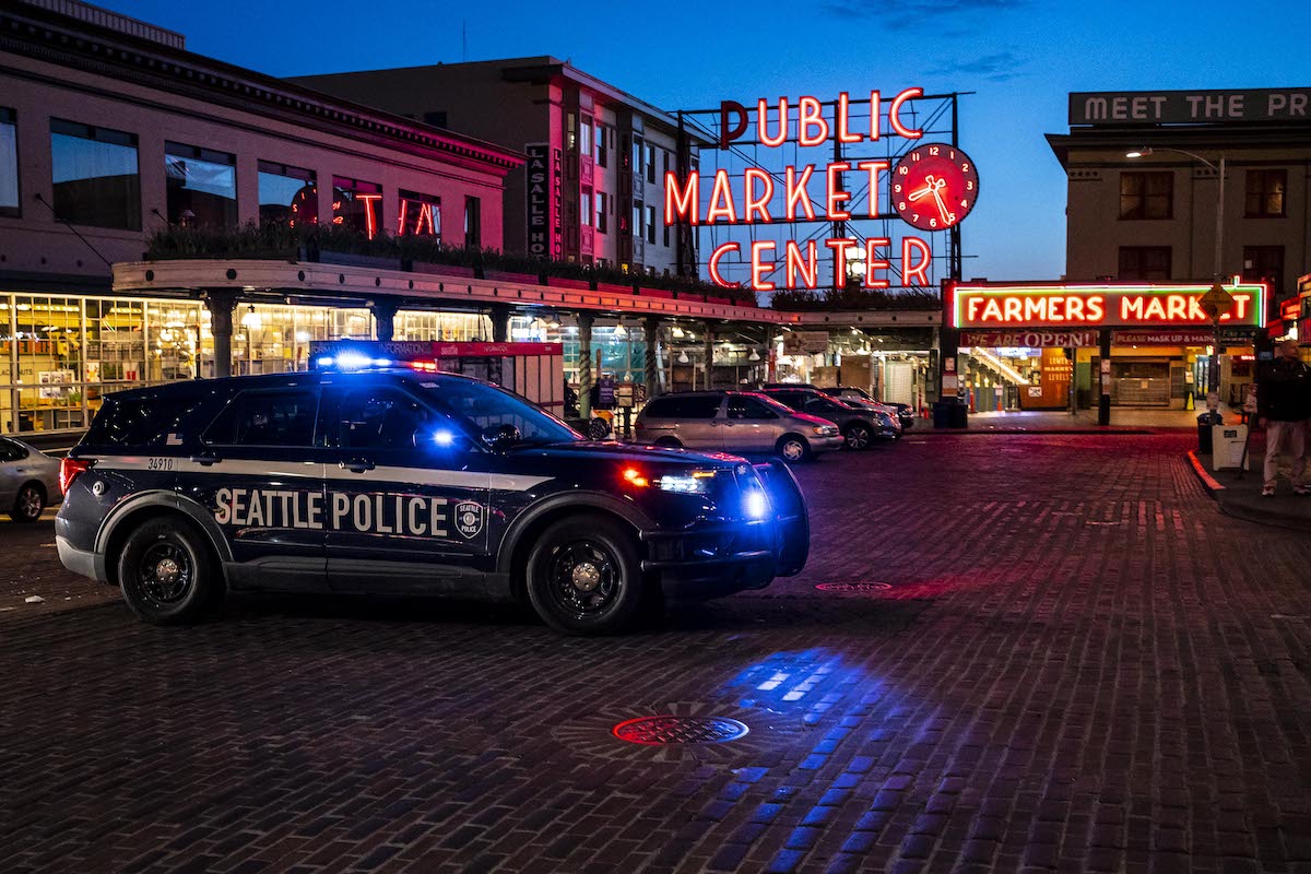 A police car sits in front of Seattle's Public Market at night.