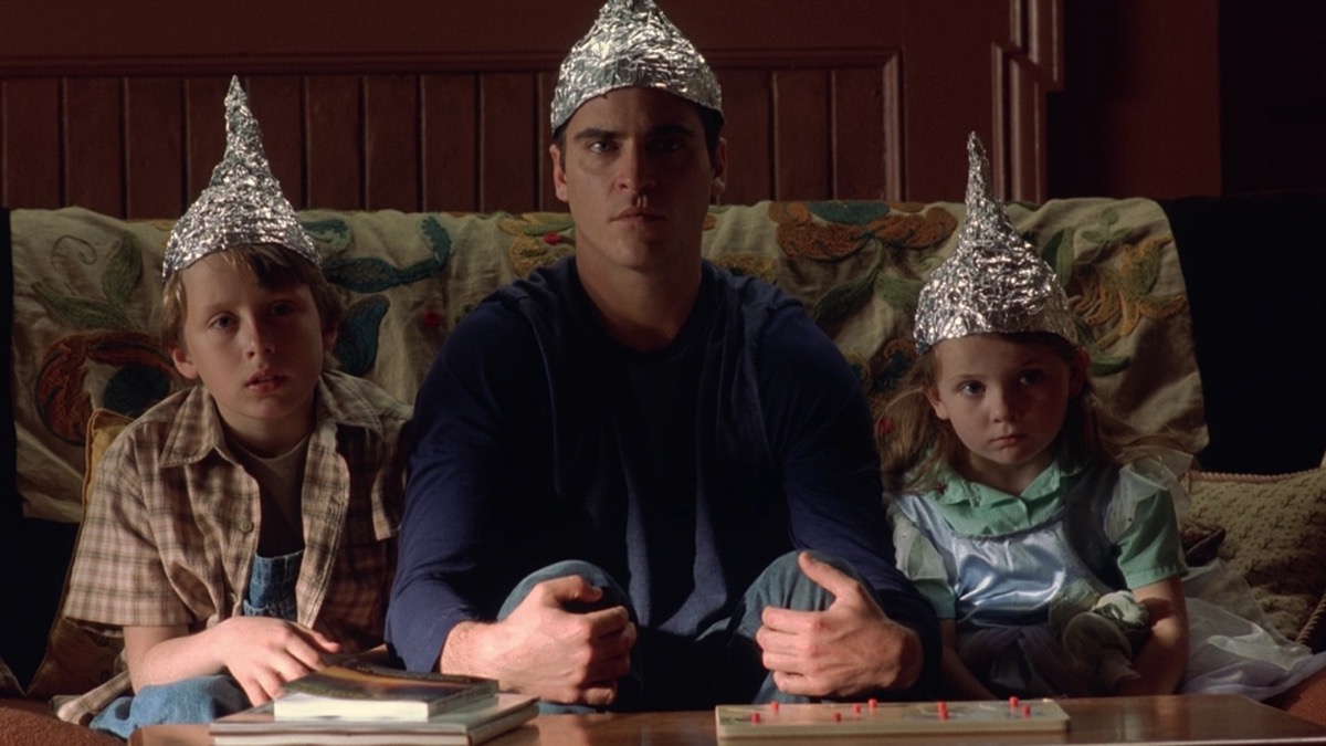 Rory Culkin, Joaquin Phoenix, and Abigail Breslin sit on a couch wearing tinfoil hats in 'Signs'.