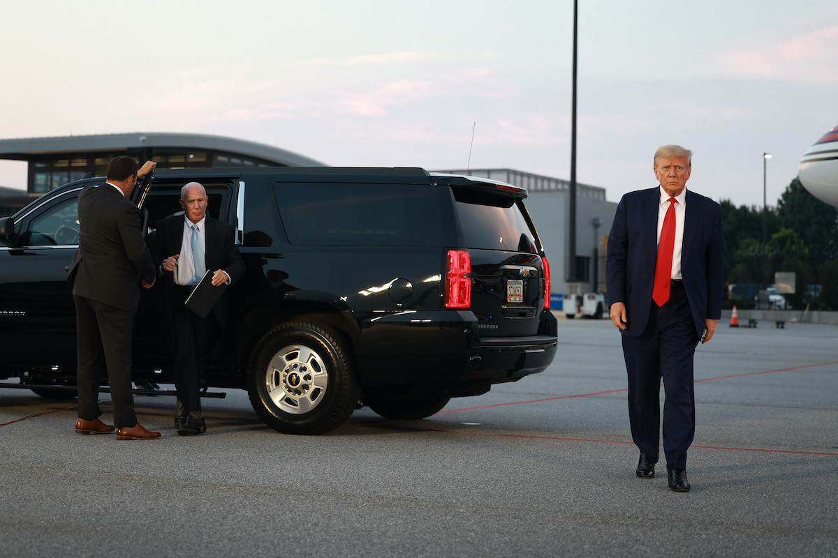 Donald Trump walks alone on an airport tarmac.