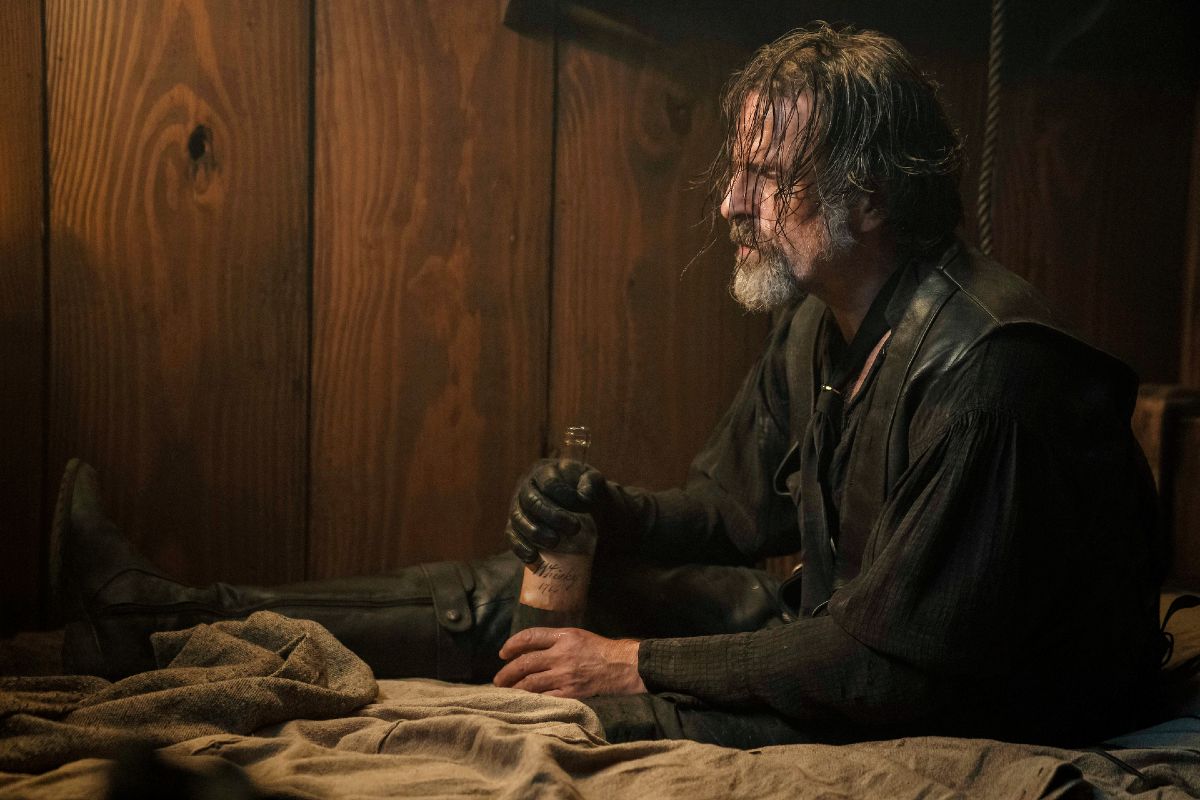 A disheveled man (Izzy Hands) holds a bottle of alcohol in 'Our Flag Means Death.'