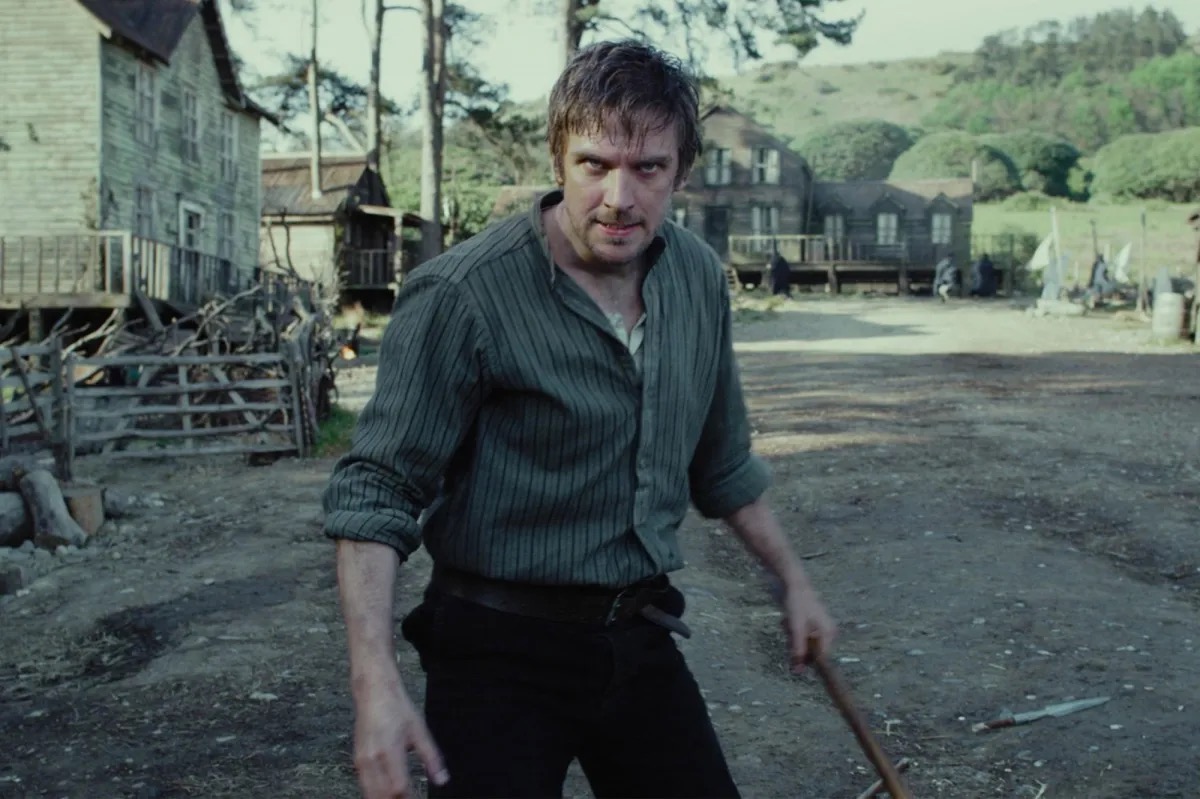 A man with an axe stands in a rural village looking ready to fight in "Apostle"