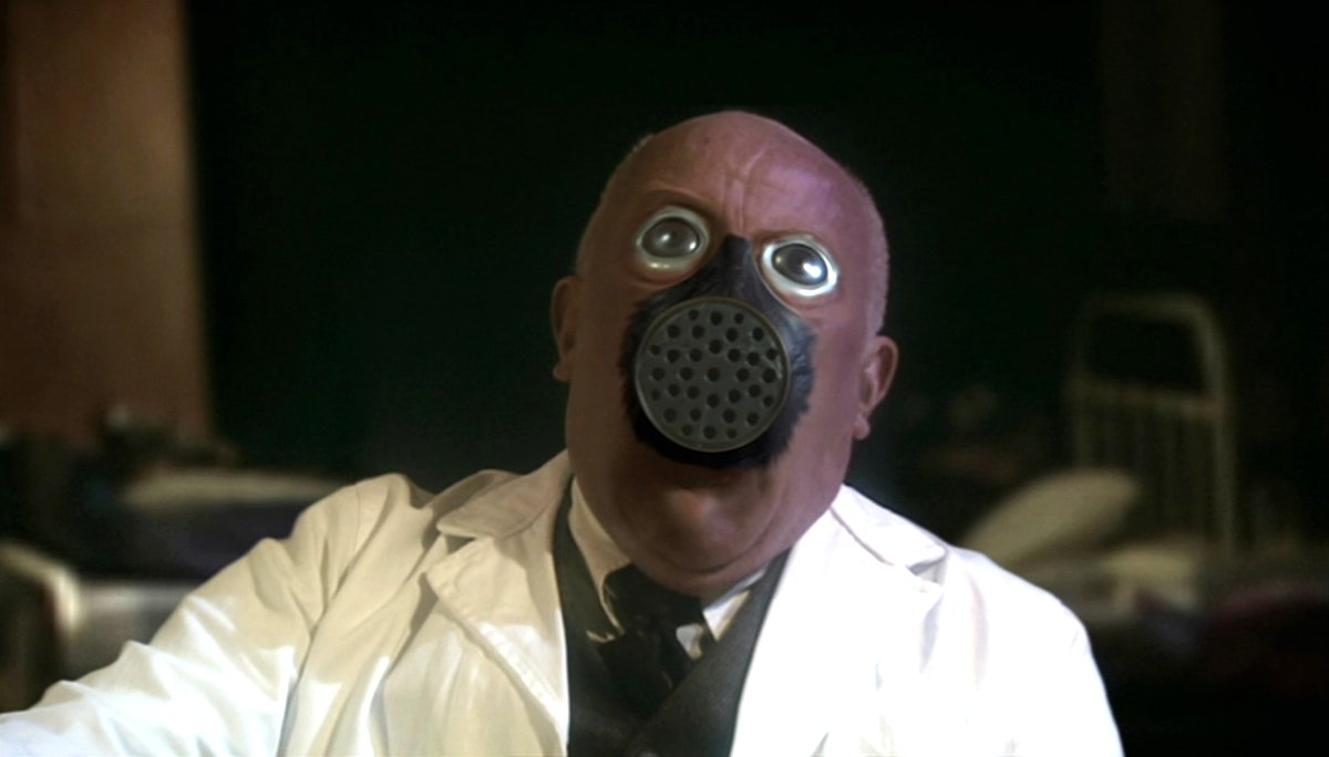 Richard Wilson as Doctor Constantine in Doctor Who, his face being replaced with a gas mask (BBC)