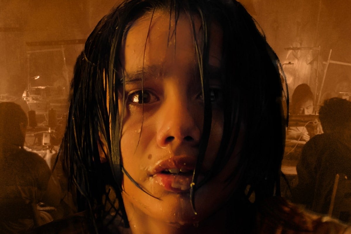 Image of Ari Lopez from the movie poster for the film, 'Dreamer.' Lopez is a young, Mexican boy with chin-length black hair and brown eyes. We see a close-up of his panicked face as he's crying and dripping with water with an image of women working at sewing machines in a sweatshop behind him. 
