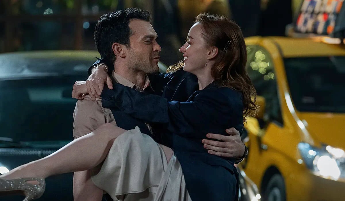 Luke (Alden Ehrenreich) holding Emily (Phoebe Dynevor) in his arms on the streets of New York in Netflix's Fair Play