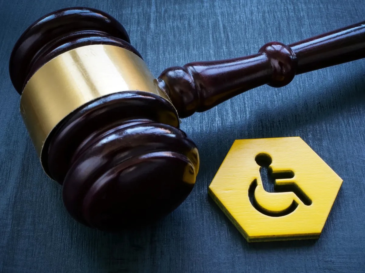 Gavel and gold haxagonal disability symbol on dark background