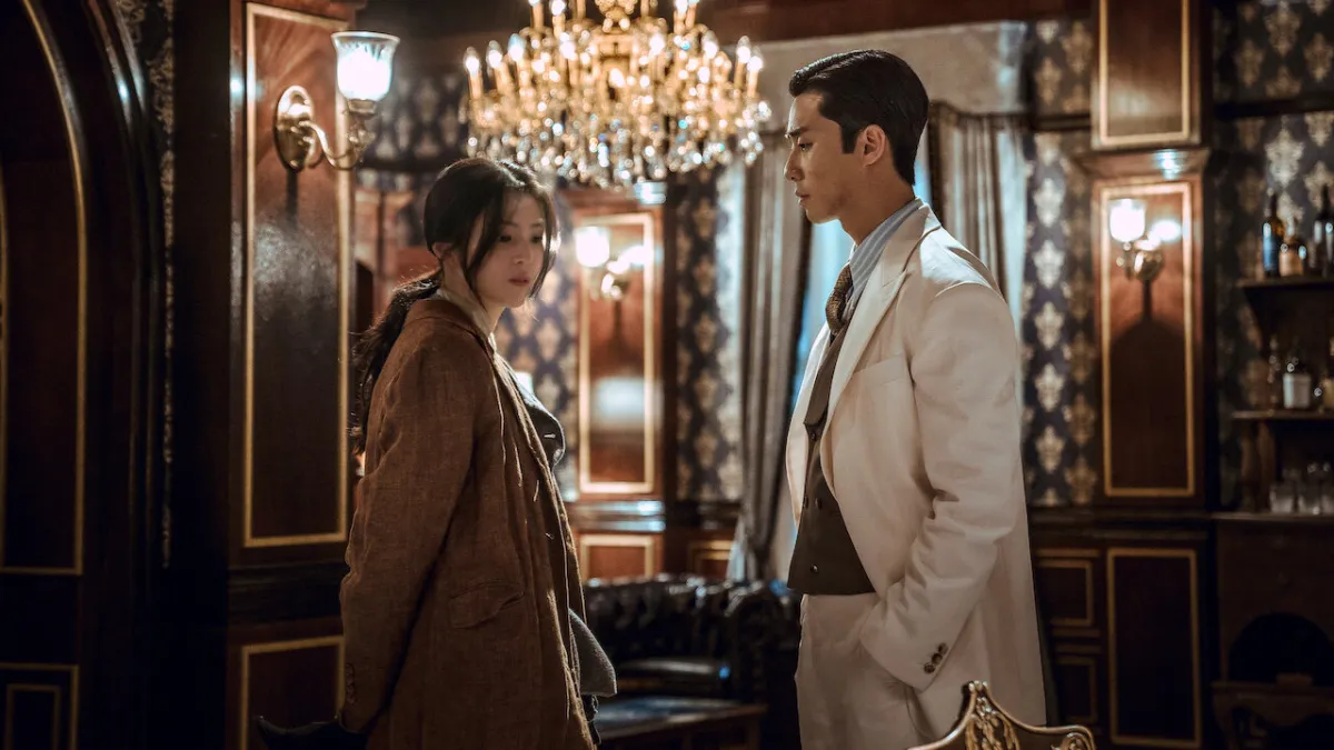 Gyeongseong Creature featuring Han So-hee on the left, standing beside Park Seo-jun in what is presumed to be his character's mansion.
