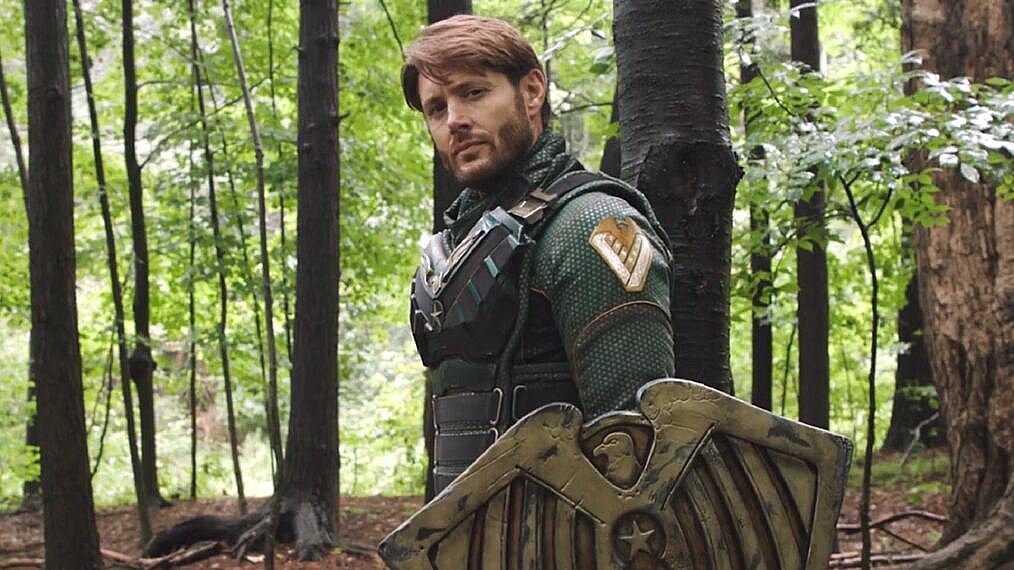 Jensen Ackles as Soldier Boy. A white man in a superhero uniform holds a sheild in the woods in 'Gen V.'