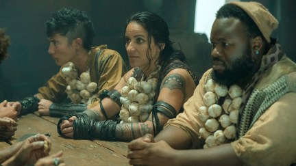 Three people sit at a table wearing garlic necklaces in 'Our Flag Means Death.'