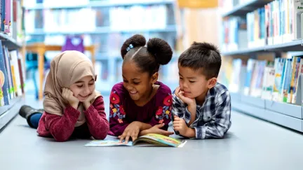 A group of three kids reading a book