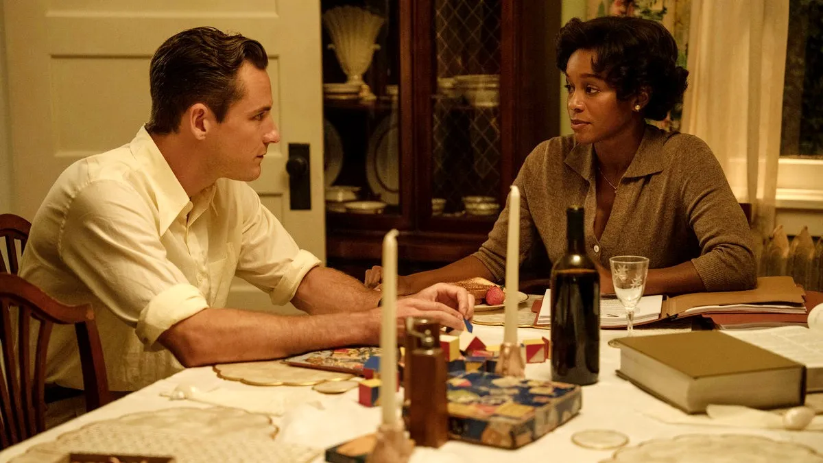Lewis Pullman as Calvin and Aja Naomi King as Harriett sit at a table in 'Lessons in Chemistry'.