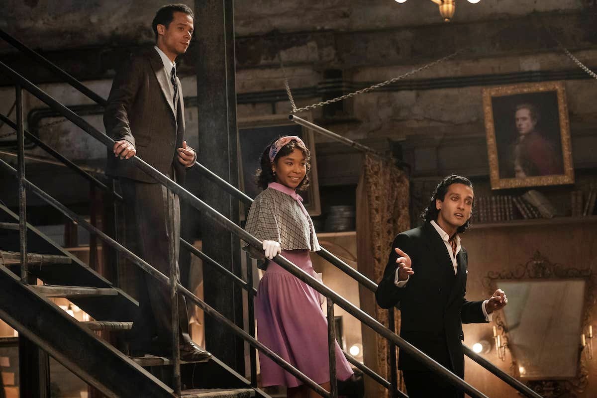 Two men and a young woman with glowing eyes walk down stairs in 'Interview with the Vampire.'