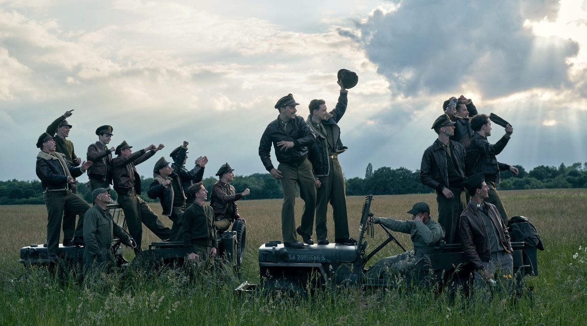 Group of World War II soldiers stand in a field in 'Masters of the Air.'