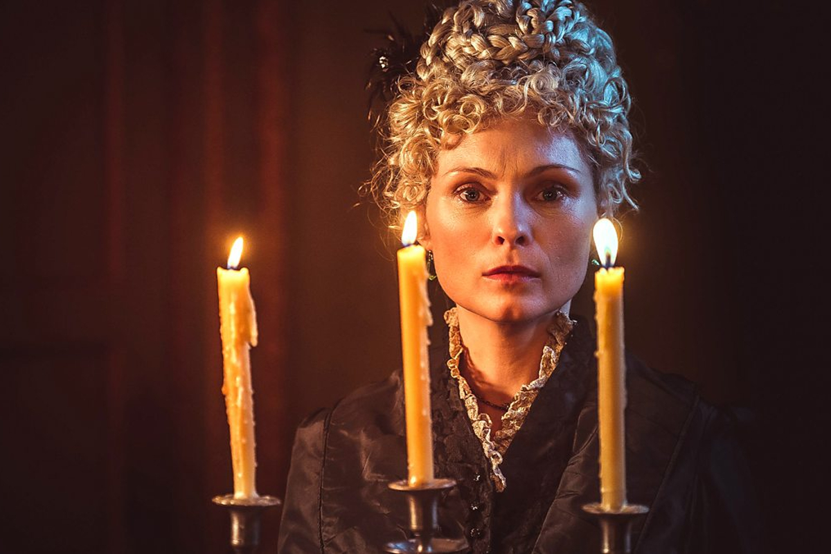 Still from A Ghost Story for Christmas: Count Magnus; MyAnna Buring holds a candelabra, her blonde hair piled on her head in an historic style.