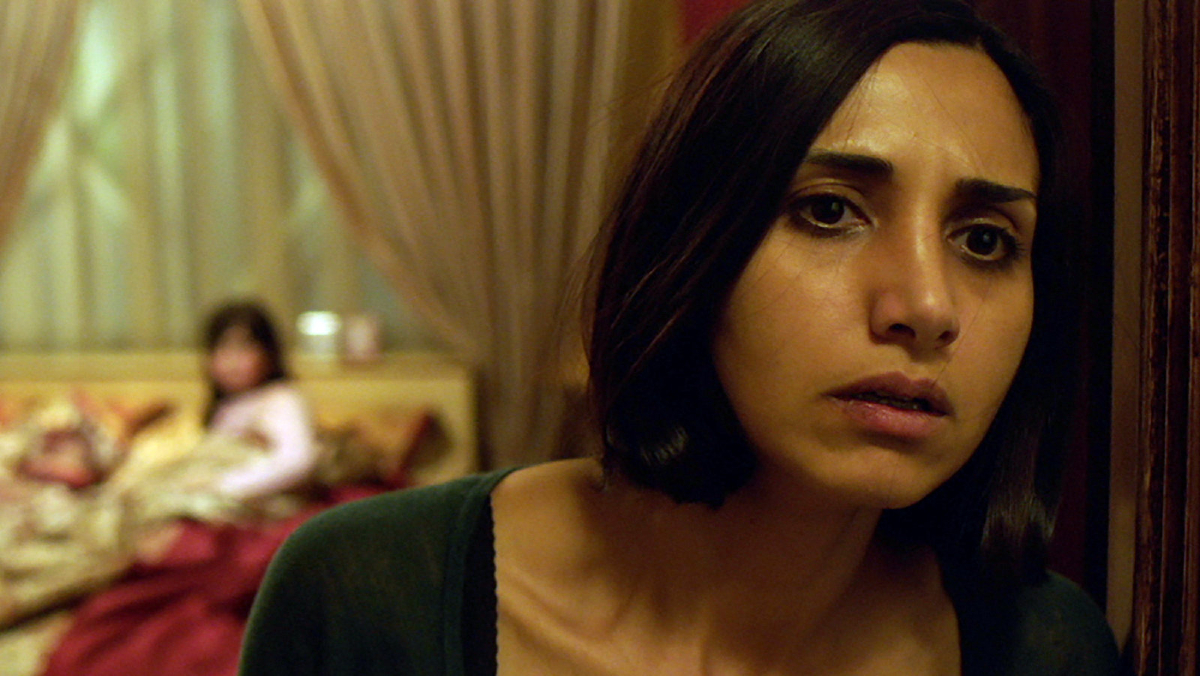 Shideh (Narges Rashidi) looks concerned while her daughter sits in the background, out of focus in 'Under the Shadow'