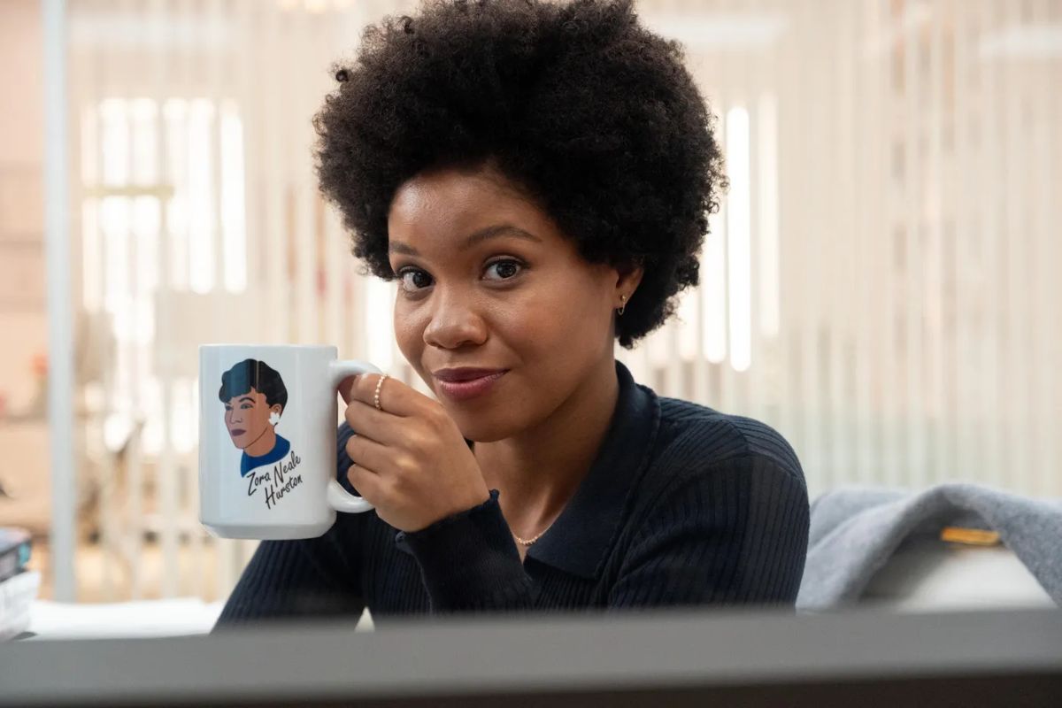 Nella in 'The Other Black Girl' holding up a mug with the face of Zora Neale Hurston. 
