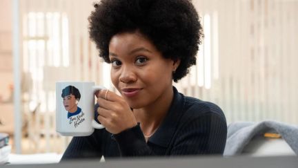 Nella in 'The Other Black Girl' holding up a mug with the face of Zora Neale Hurston.