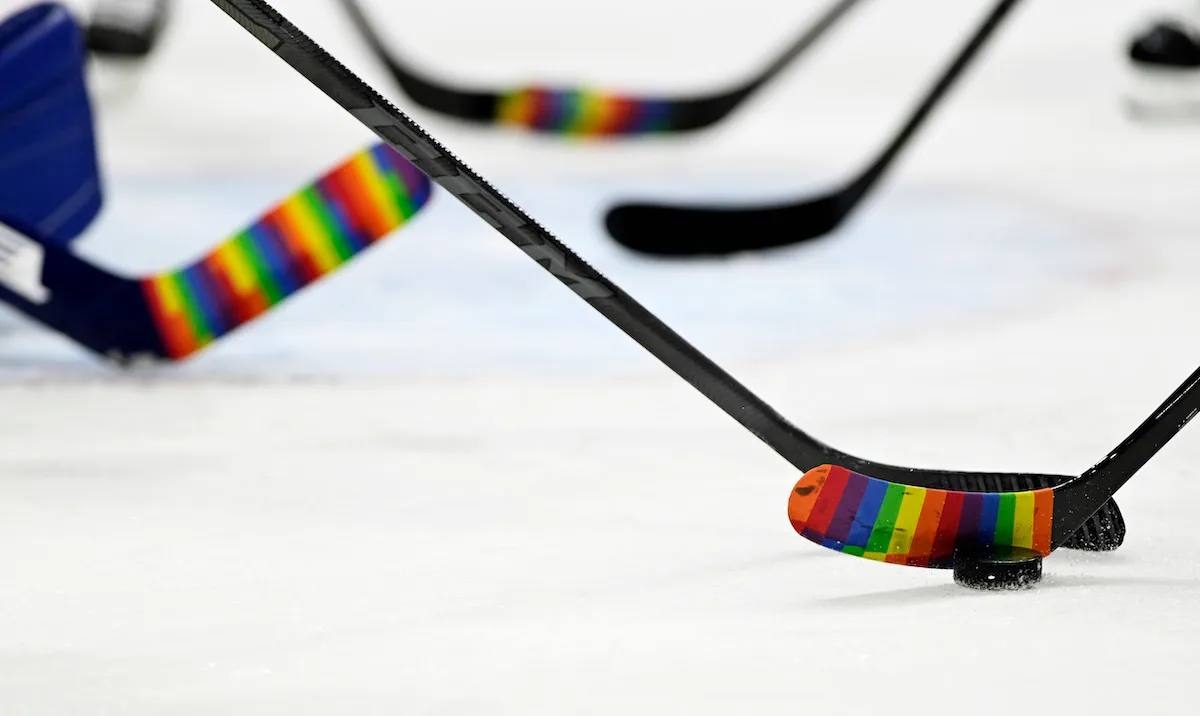 NHL hockey sticks on ice with pride tape.