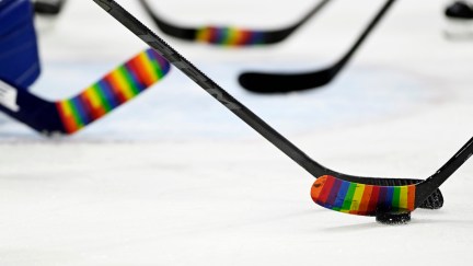 NHL hockey sticks on ice with pride tape.