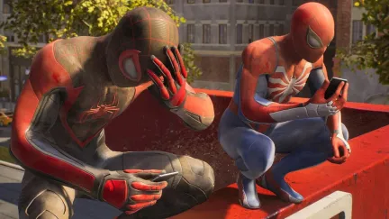 Image from the video game 'Marvel's Spider-Man 2' from Insomniac Games and Sony Interactive. Miles Morales and Peter Parker are crouched on a city rooftop in their Spider-Man suits. Miles' is black and red while Peter's is red and blue. Both are looking at their cell phones, but Miles' hand is on his forehead as if he's disturbed by something he's seeing.