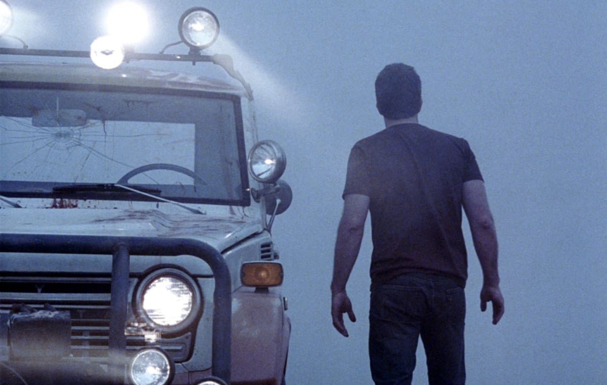A man gazes into a dense fog while standing next to his truck in 'The Mist'