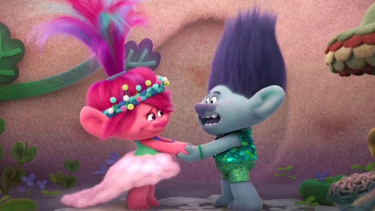 Two animated adorable trolls stand together holding hands in 'Trolls Band Together.'