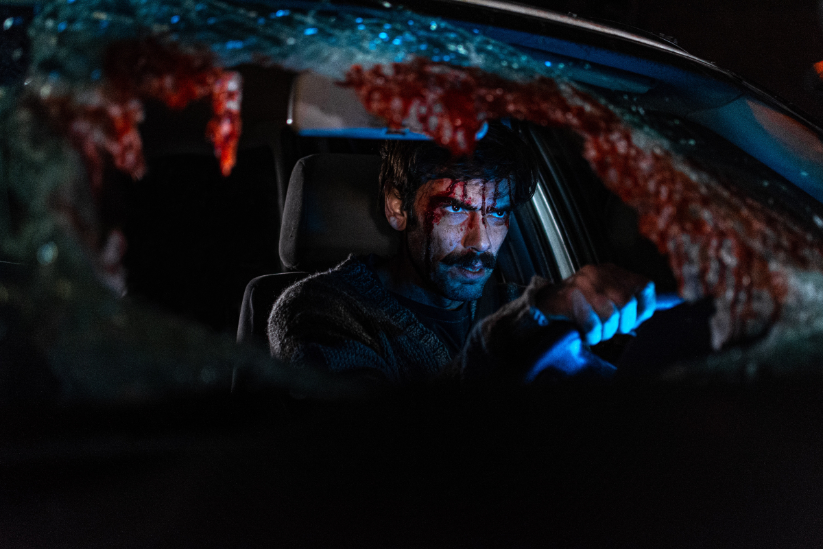 A man drives a car with a busted windshield, covered in blood, in 'When Evil Lurks'