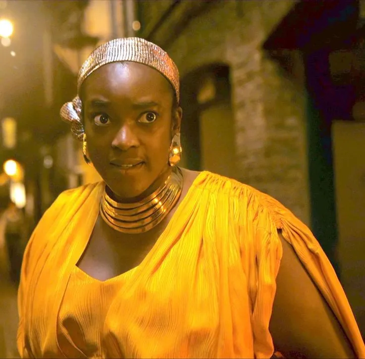 A woman wears a yellow flowing dress and scarf around her hair in 'Loki.'