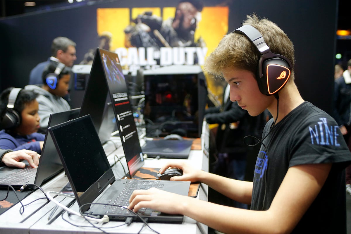 A young gamer plays a Call of Duty game on a laptop.