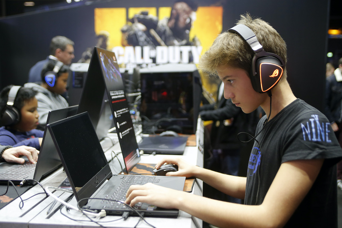 A young gamer plays a Call of Duty game on a laptop.