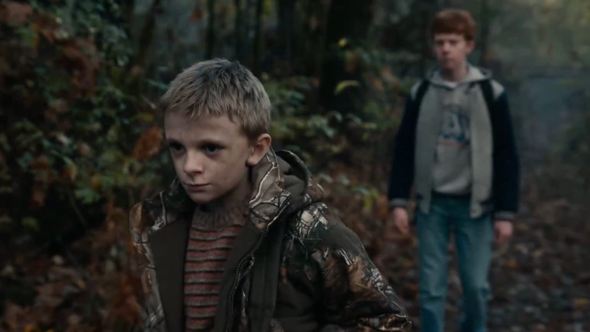 A little boy walks away from another boy and into the woods in "Antlers"