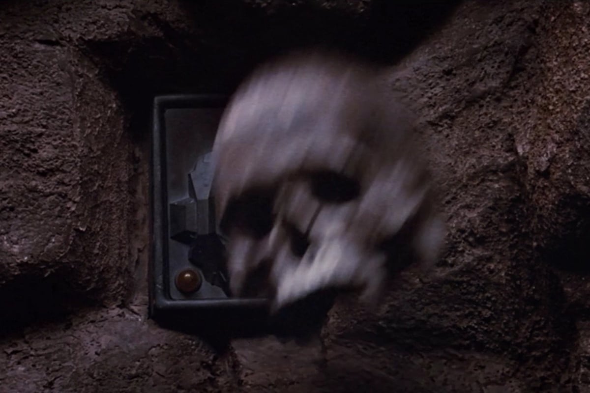 Still from Return of the Jedi; a skull in motion, being thrown against a control panel on the wall of a cave.