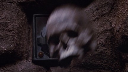 Still from Return of the Jedi; a skull in motion, being thrown against a control panel on the wall of a cave.