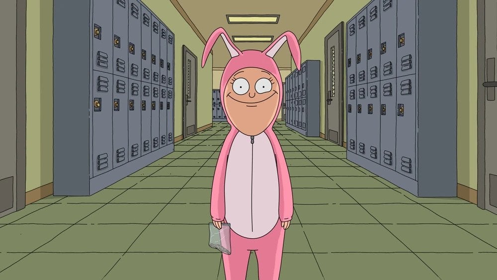 Still from Bob's Burgers episode Fort Night;  Millie stands in the hallway at Wagstaff, wearing a pink bunny costume and a disturbing smile.