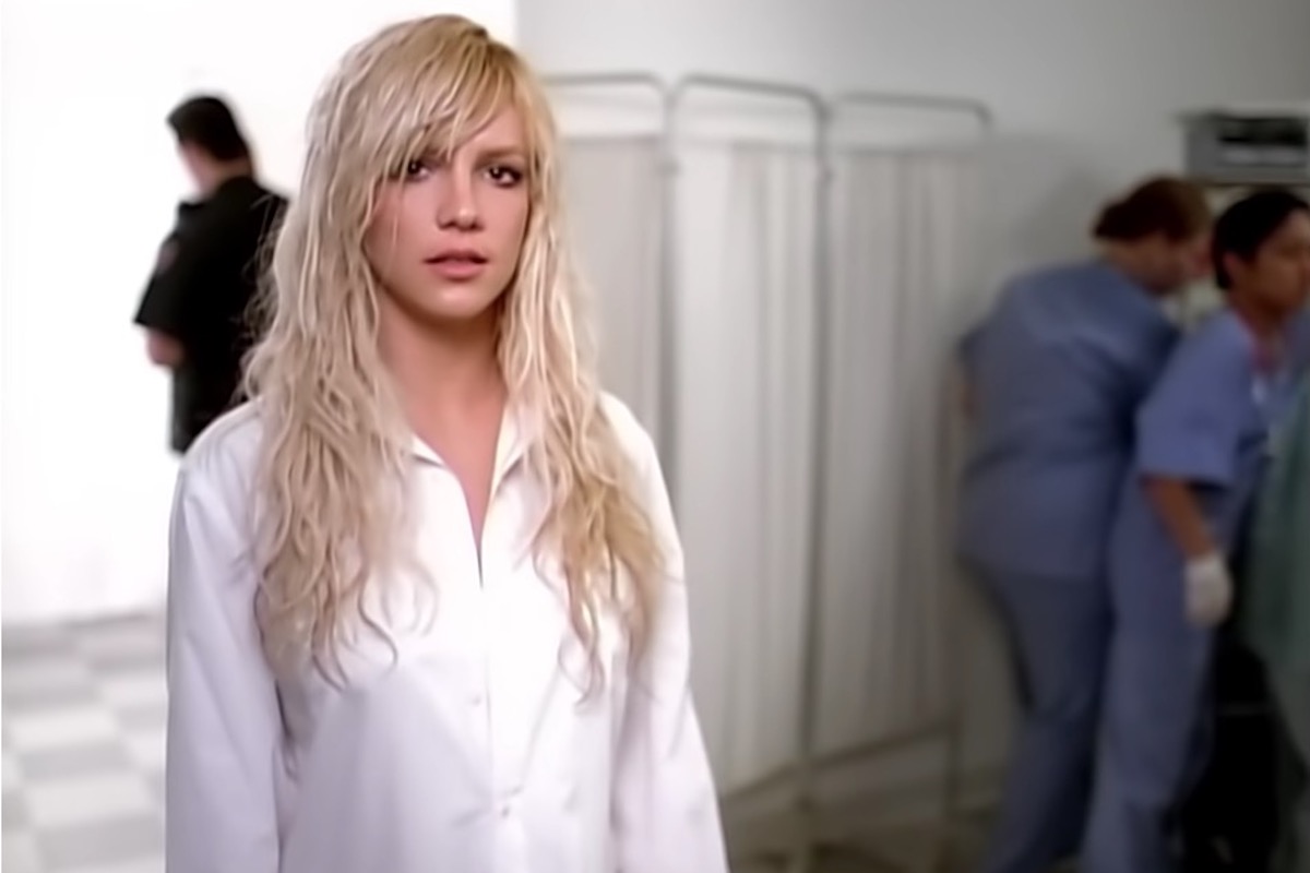 In a music video, Britney Spears sings, surrounded by police and medical staff.